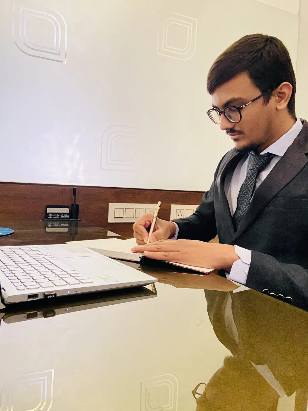 A team member making written notes beside a laptop at a desk in the Rajkot office