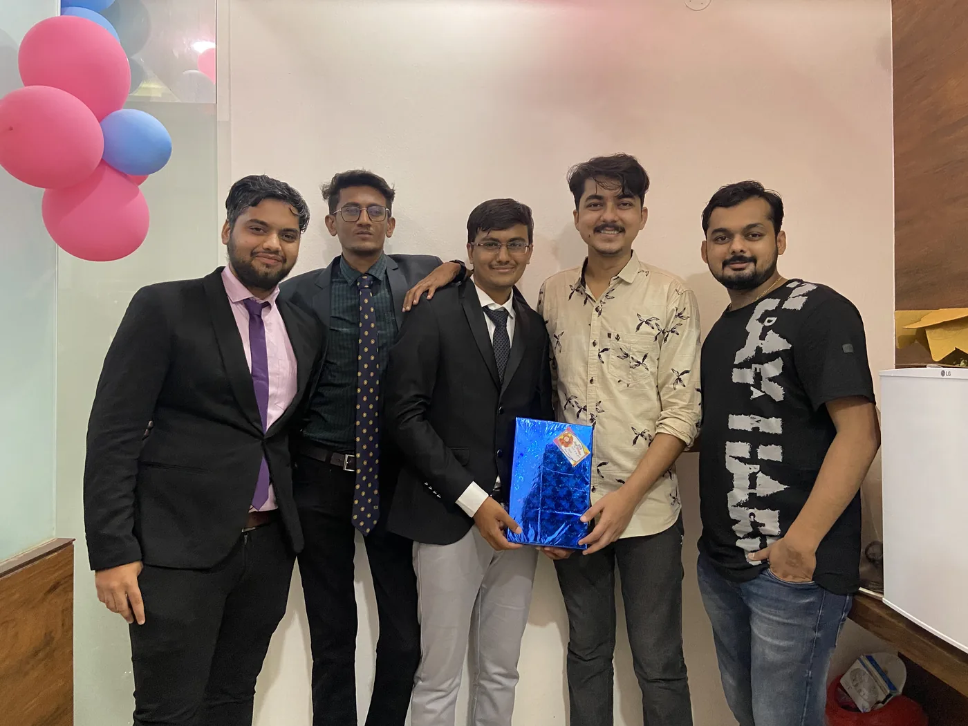 The team gathered in the office as a gift is presented to a colleague